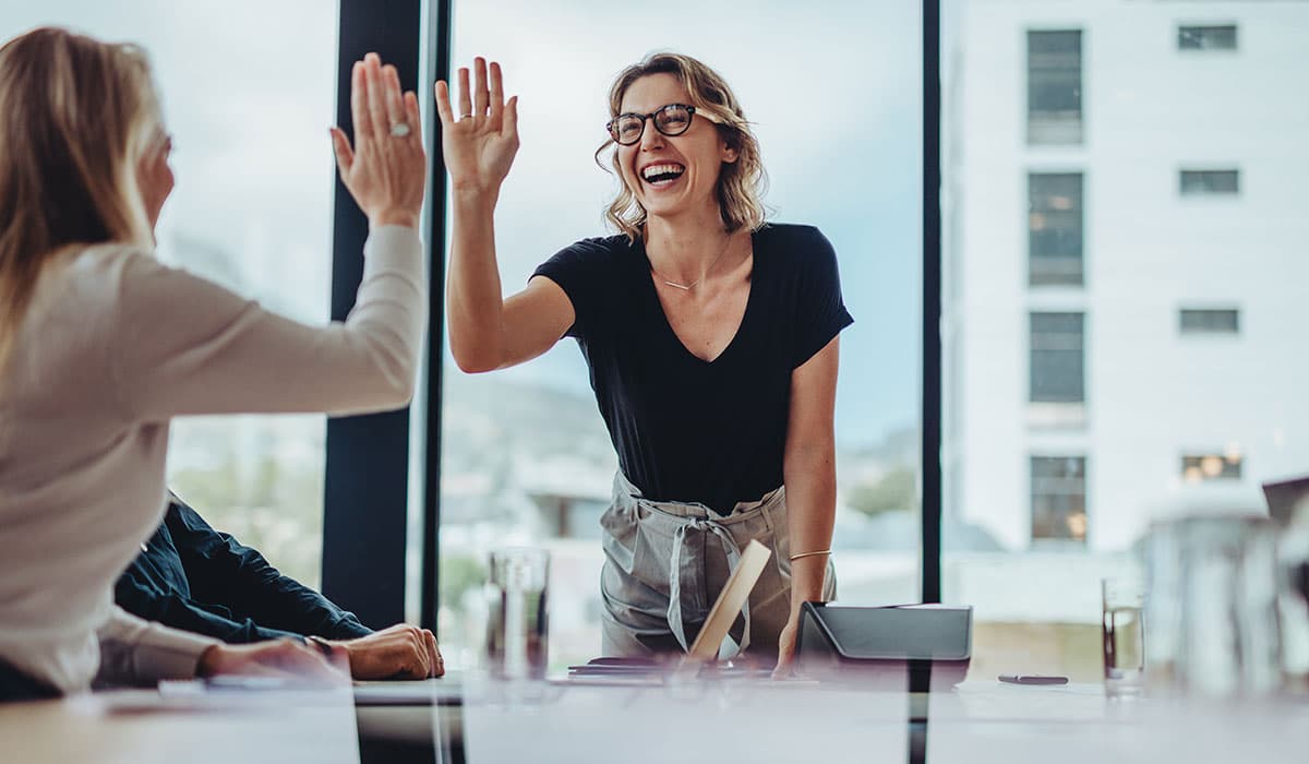 Two of Alation's Data Intelligence Project students smiling as they are about to high-five each other