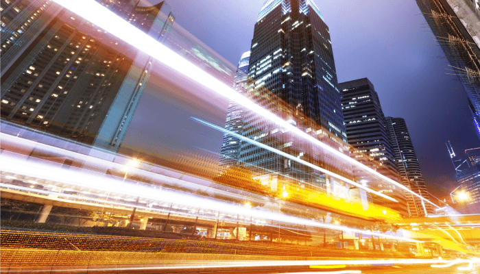 Alation blog image: Long exposure night photography of a busy cityscape with light trails from traffic and illuminated skyscrapers.